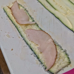 Top zucchini slices with Emmental cheese and ham