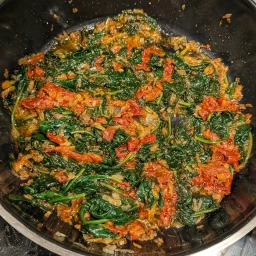 Zwiebeln, Knoblauch, Tomatenmark und getrocknete Tomaten und Spinat